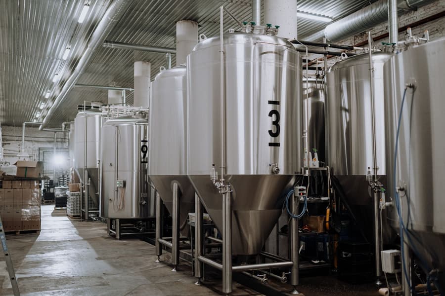 Stainless fermenters in a row under a steel roof