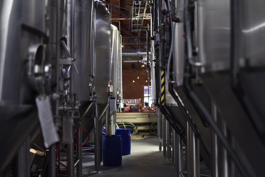 Looking down the corridor between the fermenters to drinkers at the bar at the far end
