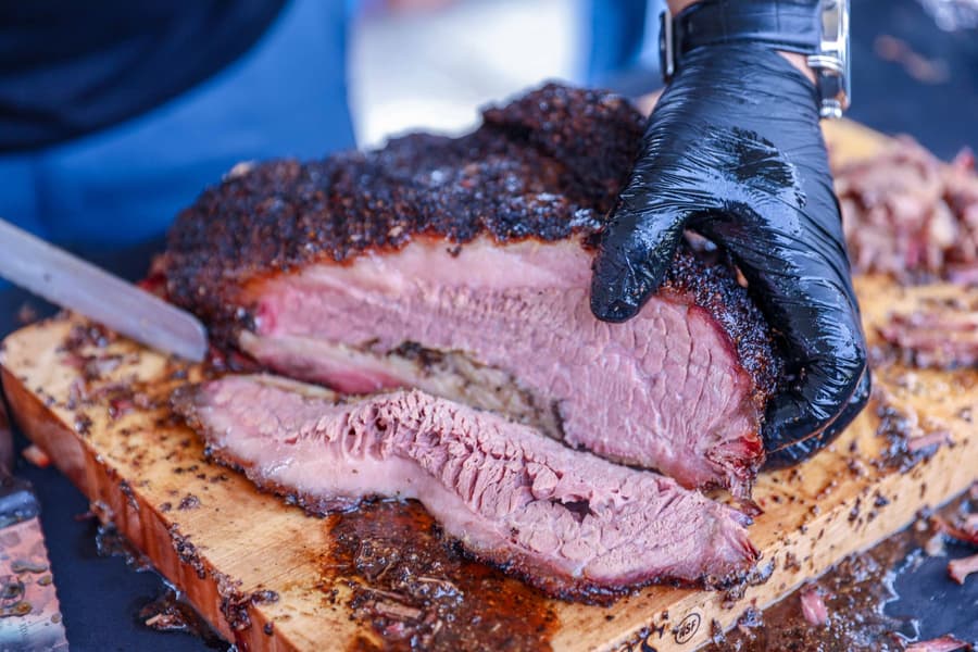 Brisket with a black bark being sliced on a board