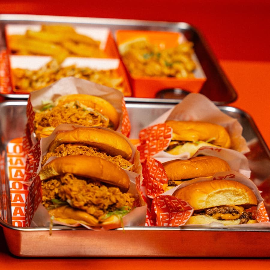 Trays of burgers and fries on a steel bench