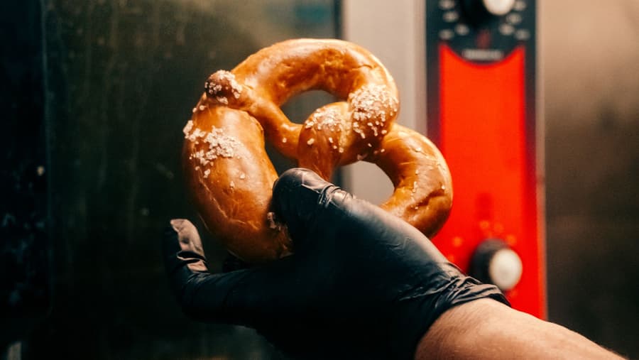 A spent-grain pretzel held in a gloved hand