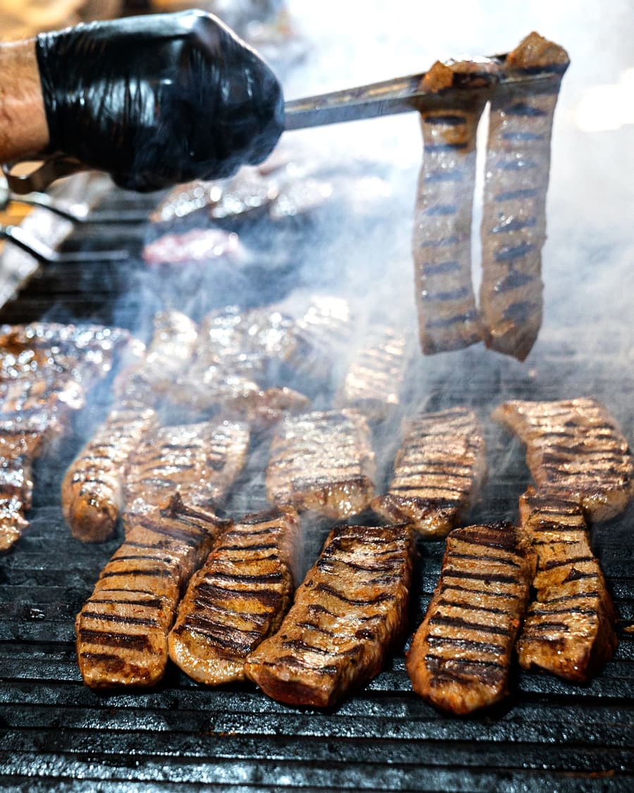 Steaks turned with tongs over a hot grill