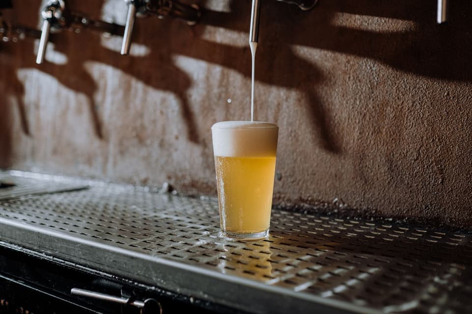 A pale ale on the steel drip tray under the taps