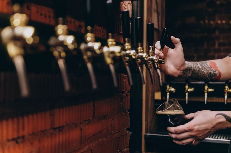 Railside Red pouring dark into a glass under a row of brass taps