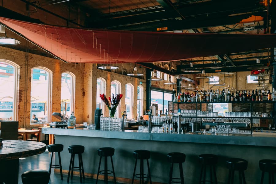 The Hall: brick arched windows, a long concrete bar and a red sail strung under the roof