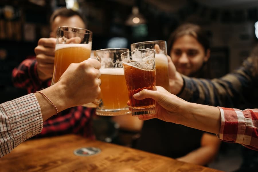 Four pints raised in a toast across a timber table