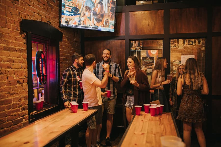 Friends laughing over a cup game on the long timber tables